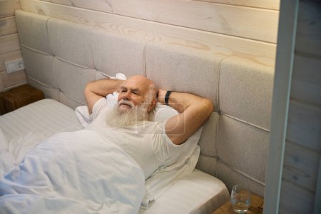 Foto de El anciano está descansando en una acogedora cama en el dormitorio, la habitación tiene un interior minimalista - Imagen libre de derechos