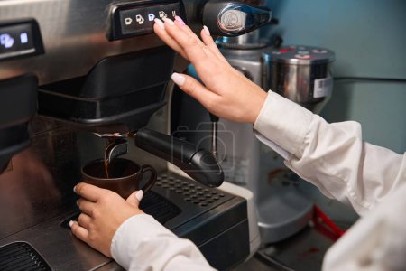 Photo for Woman barista prepares coffee in a coffee machine, modern equipment is used - Royalty Free Image