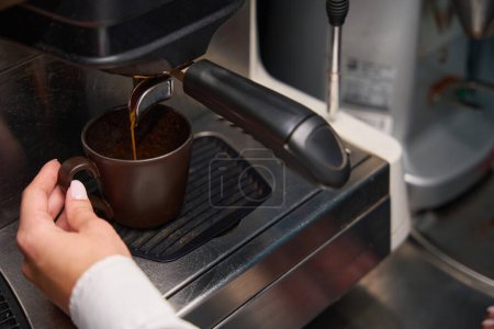 Téléchargez les photos : Femme barista prépare le café dans une machine à café, en utilisant un équipement moderne - en image libre de droit