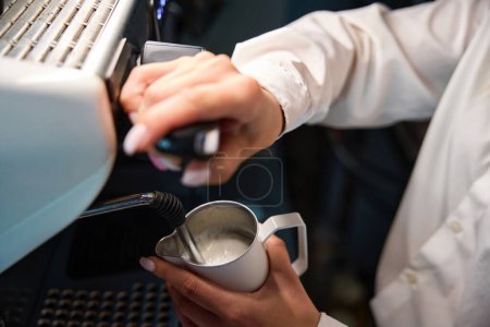 Téléchargez les photos : Barista prépare le café avec de la mousse de lait dans une machine à café, en utilisant un équipement moderne - en image libre de droit