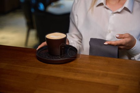 Téléchargez les photos : Serveuse met une tasse de café sur le comptoir du bar, la femme a une manucure soignée - en image libre de droit