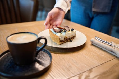 Foto de Camarera sirve postre para una persona, pastel y café se sirven - Imagen libre de derechos