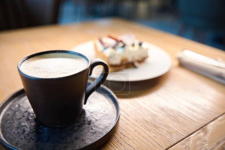 Foto de Una taza de café y un plato de tarta están sobre la mesa, el postre se sirve para una persona - Imagen libre de derechos