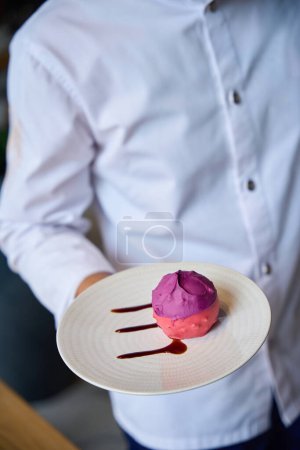 Téléchargez les photos : Employé de cuisine restaurant présente un gâteau rose, le plat est servi avec de la sauce scolaire - en image libre de droit