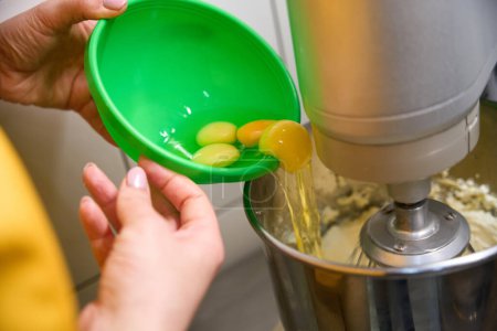 Photo for Closeup of female pastry chef hands adding egg whites and yolks into mixing bowl - Royalty Free Image