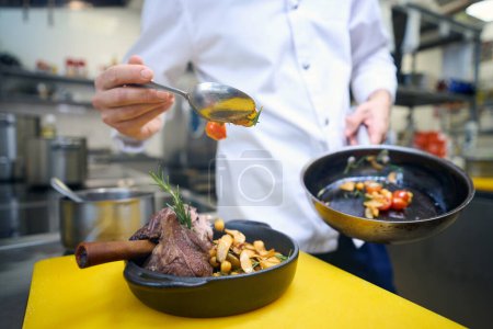 Foto de Empleado de cocina prepara carne con verduras y salsa para servir, utiliza productos de alta calidad - Imagen libre de derechos