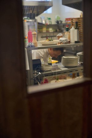 Man is at his workplace in a restaurant kitchen, he is at the rack with dishes