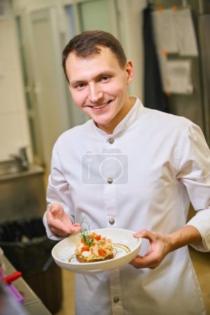 Foto de Restaurante empleado de cocina presenta tostadas con aguacate y camarones, el plato se sirve con microgreens - Imagen libre de derechos