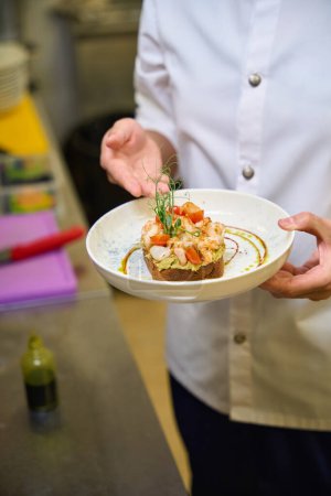 Foto de Chef presenta tostadas con aguacate y camarones, el plato se sirve con microgreens - Imagen libre de derechos