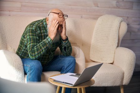 Photo for Old man is tired, working with documents in the living room, he has a headache - Royalty Free Image