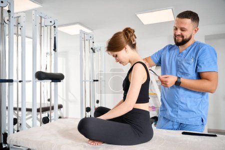 Photo for Kinesiologist glues black tape to the back of a patient, a woman in comfortable black clothes - Royalty Free Image