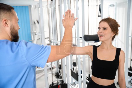 Téléchargez les photos : Physiothérapeute saluant patiente dans la salle de gym, femme portant des vêtements noirs confortables - en image libre de droit
