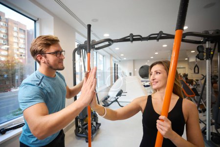 Téléchargez les photos : Femme et hommes se saluent dans la salle de gym, ils ont des bâtons de sport spéciaux dans leurs mains - en image libre de droit