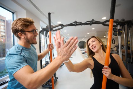 Téléchargez les photos : Belle femme accueille un homme dans la salle de gym, ils ont des bâtons de sport spéciaux dans leurs mains - en image libre de droit