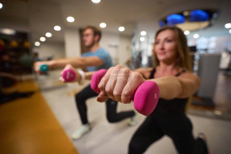 Foto de La gente realiza ejercicios con pesas, están en un gimnasio moderno - Imagen libre de derechos