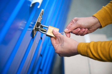 Photo for Woman uses keys to open the lock on the door of a storage room. - Royalty Free Image