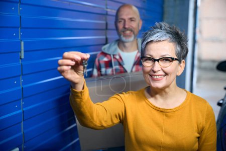 Photo for Woman with short hair and glasses shows keys to storage room - Royalty Free Image