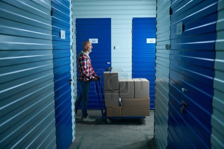 Téléchargez les photos : Un homme en chemise à carreaux transporte des choses dans une salle de stockage - en image libre de droit