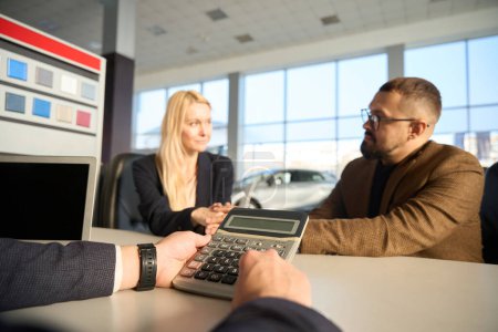 Photo for Woman and a guy are sitting at a table in front of a car salesman - Royalty Free Image