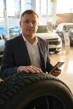 Photo for Guy who sells cars looks directly at the camera in a dealership - Royalty Free Image