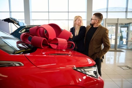Téléchargez les photos : Dame caucasienne reçoit une voiture rouge comme un cadeau de son mari - en image libre de droit
