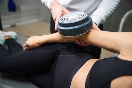 Photo for Magnetic therapy process. Professional man holding magnet device, doing procedure for arm to woman - Royalty Free Image