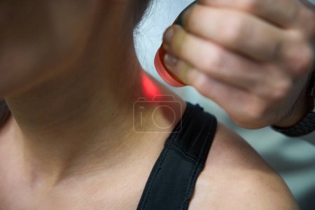 Photo for Woman undergoing laser therapy for reduction of swelling and inflammation on neck - Royalty Free Image