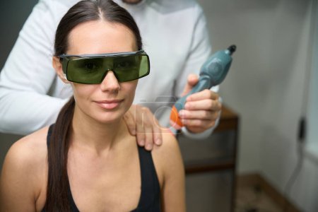 Téléchargez les photos : Femme faisant l'objet d'une thérapie laser pour réduire l'enflure et l'inflammation du bras - en image libre de droit