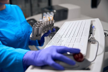 Foto de Empleado de laboratorio utiliza equipos modernos para analizar biomaterial, las muestras están etiquetadas - Imagen libre de derechos