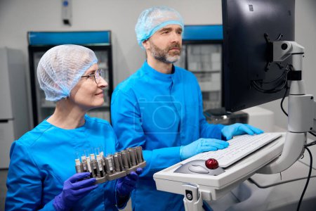 Inmunólogo masculino y su colega utilizan equipos de alta tecnología en el trabajo, personas en un laboratorio moderno