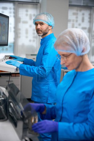 Labormitarbeiter arbeiten mit High-Tech-Geräten, Menschen in blauen Uniformen