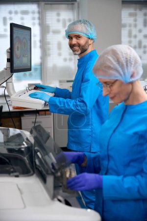 Laborassistenten setzen bei ihrer Arbeit Hightech-Geräte ein, Menschen in blauen Uniformen