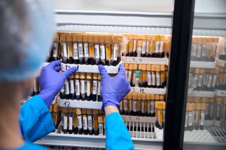 Photo for Laboratory technician holds a set with biomaterial for blood analysis in his hands, samples are stored in the refrigerator - Royalty Free Image