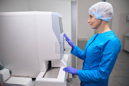 Téléchargez les photos : Spécialiste des maladies infectieuses féminine travaille dans un laboratoire sur un équipement moderne, une femme en uniforme bleu - en image libre de droit