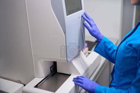 Foto de Especialista en enfermedades infecciosas trabaja en un laboratorio en equipos modernos, una mujer en uniforme azul - Imagen libre de derechos