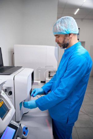 Foto de Especialista trabaja en un aparato de extracción automática de ácidos nucleicos, un hombre con guantes de protección - Imagen libre de derechos