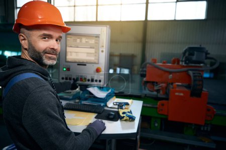 Mann mittleren Alters in einer Werkstatt am Arbeitsplatz mit modernen Geräten