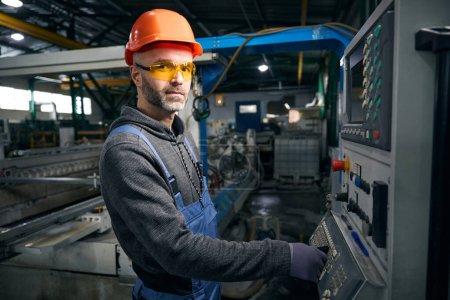Foto de El empleado de producción de ventanas trabaja en equipos de alta tecnología, un hombre con gafas de seguridad - Imagen libre de derechos