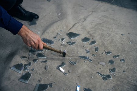 Téléchargez les photos : Homme brise le verre triplex avec un marteau, les caractéristiques de la technologie triplex sont visibles - en image libre de droit
