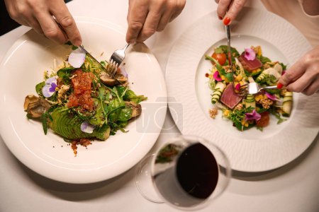 Téléchargez les photos : Les gens profitent d'un délicieux dîner dans un restaurant confortable, salade légère et vin servi - en image libre de droit