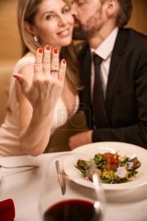 Téléchargez les photos : Happy lady montre une bague sur sa main, son compagnon l'embrasse tendrement - en image libre de droit