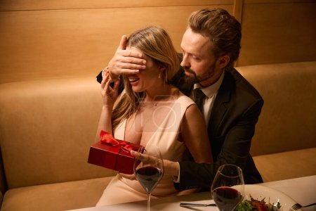 Téléchargez les photos : Surprise pour une charmante dame lors d'un dîner romantique, cadeau dans une boîte rouge - en image libre de droit