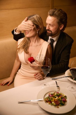 Téléchargez les photos : L'homme donne à une femme une petite boîte rouge, le couple s'assoit à une table dans un restaurant - en image libre de droit