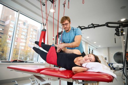 Photo for Instructor fixes a woman in a suspended loop system on a rareboard, using modern healing techniques - Royalty Free Image