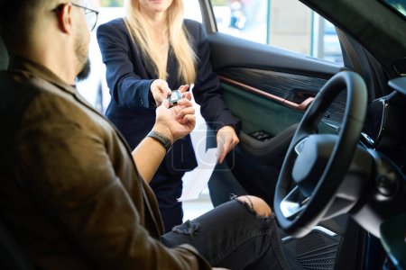 Téléchargez les photos : Femme vendeur donne les clés d'une nouvelle voiture aux mains de l'acheteur - en image libre de droit