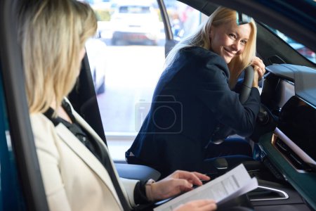Photo for Smiling woman buyer leans on the steering wheel of a car - Royalty Free Image