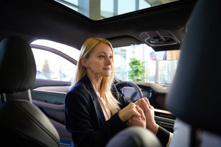 Téléchargez les photos : Jeune femme blonde assise dans une voiture tient ses maris mains dans ses mains - en image libre de droit