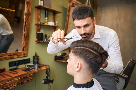 Téléchargez les photos : Homme client se faisant couper les cheveux par coiffeur au salon de coiffure - en image libre de droit