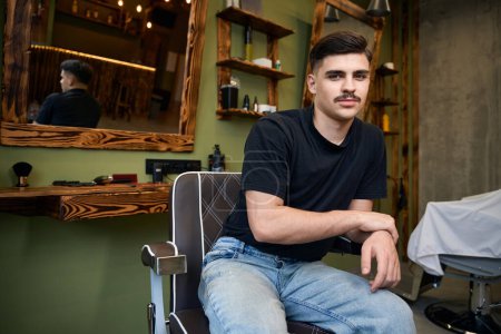 Foto de Peluquería masculina profesional esperando al cliente sentado en la silla en la barbería - Imagen libre de derechos