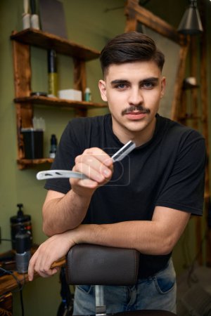 Photo for Professional man barber with razor in hands in barbershop - Royalty Free Image